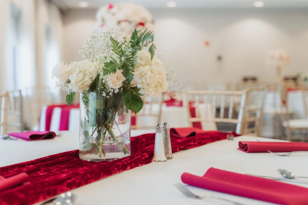 reception table red velvet runner white rose vase