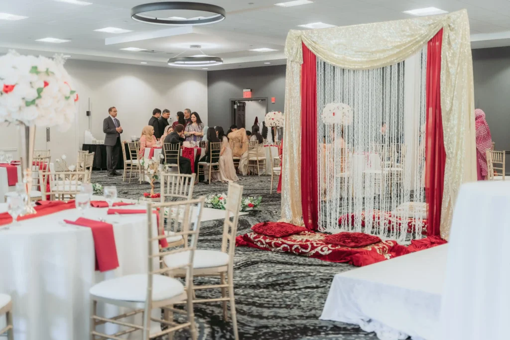 wedding reception hall guests seated red white decor