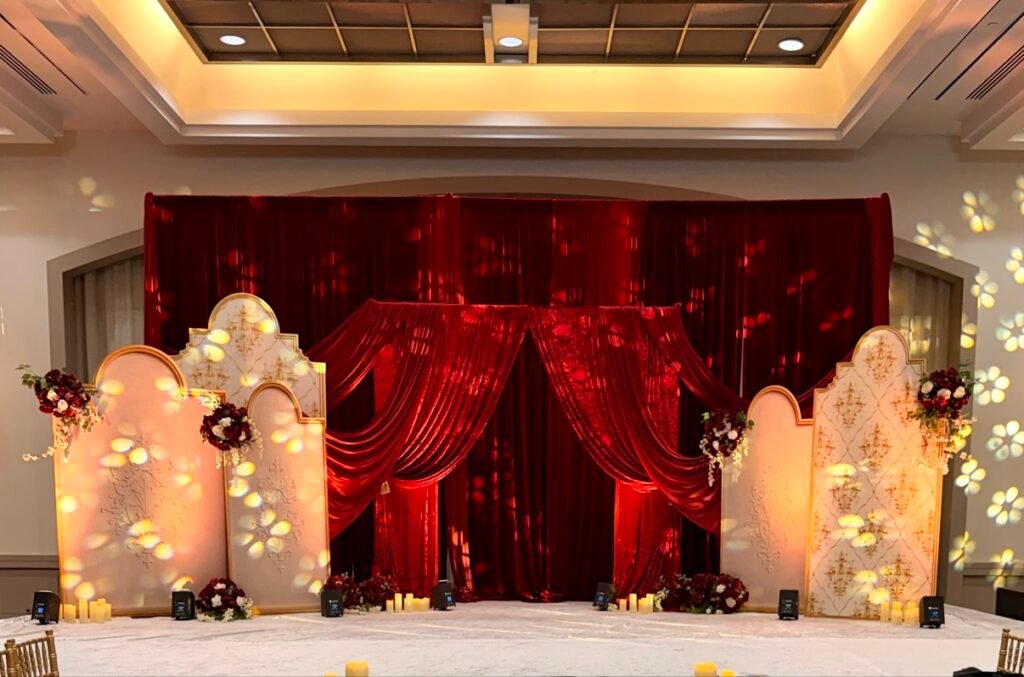 Red velvet wedding stage with gold arched panels by Regal Event Decor
