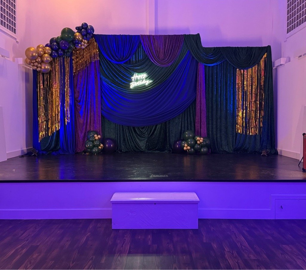 Navy and purple birthday stage with balloon garland and neon Happy Birthday sign by Regal Event Decor