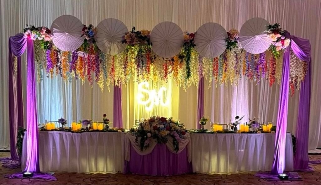 Lavender head table with white parasols and neon SM sign by Regal Event Decor