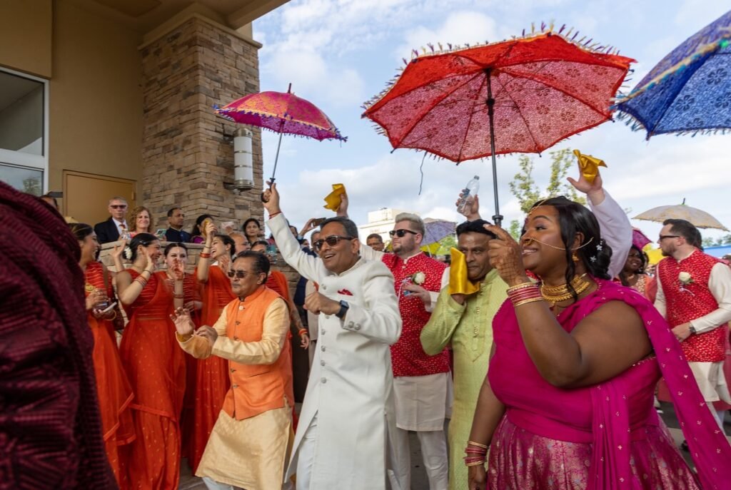 Outdoor baraat procession at a New Jersey Indian wedding — dancing guests and colorful umbrellas, decor by Regal Event Decor