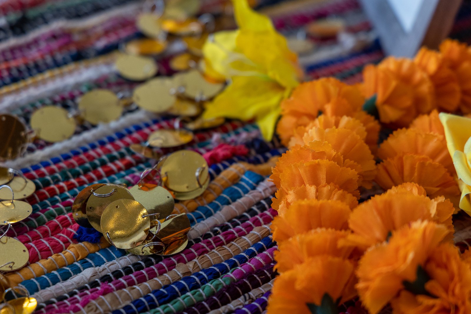 Close-up sangeet table detail by Regal Event Decor — marigolds and gold discs on a handwoven textile, Indian wedding decor New Jersey