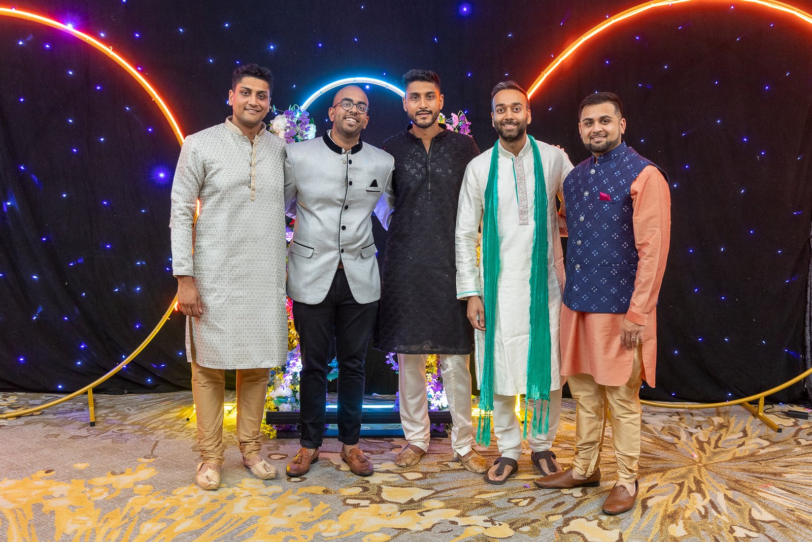 Guests posing at the neon arch sangeet backdrop designed by Regal Event Decor, fusion wedding New Jersey