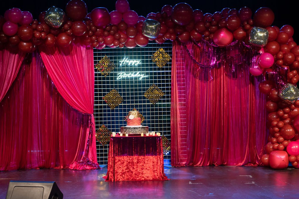 Ruby draped stage Pittsburgh — wide shot of red drape stage installation, luxury milestone birthday decor